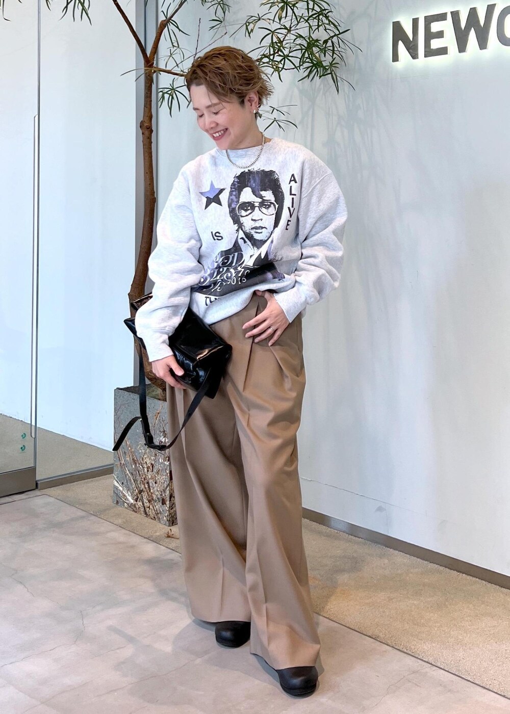 ベージュ系のスラックス、ブラック系のショルダーバッグ、ブラック系のスニーカーを着用したレディースの秋コーディネートの2枚目の写真