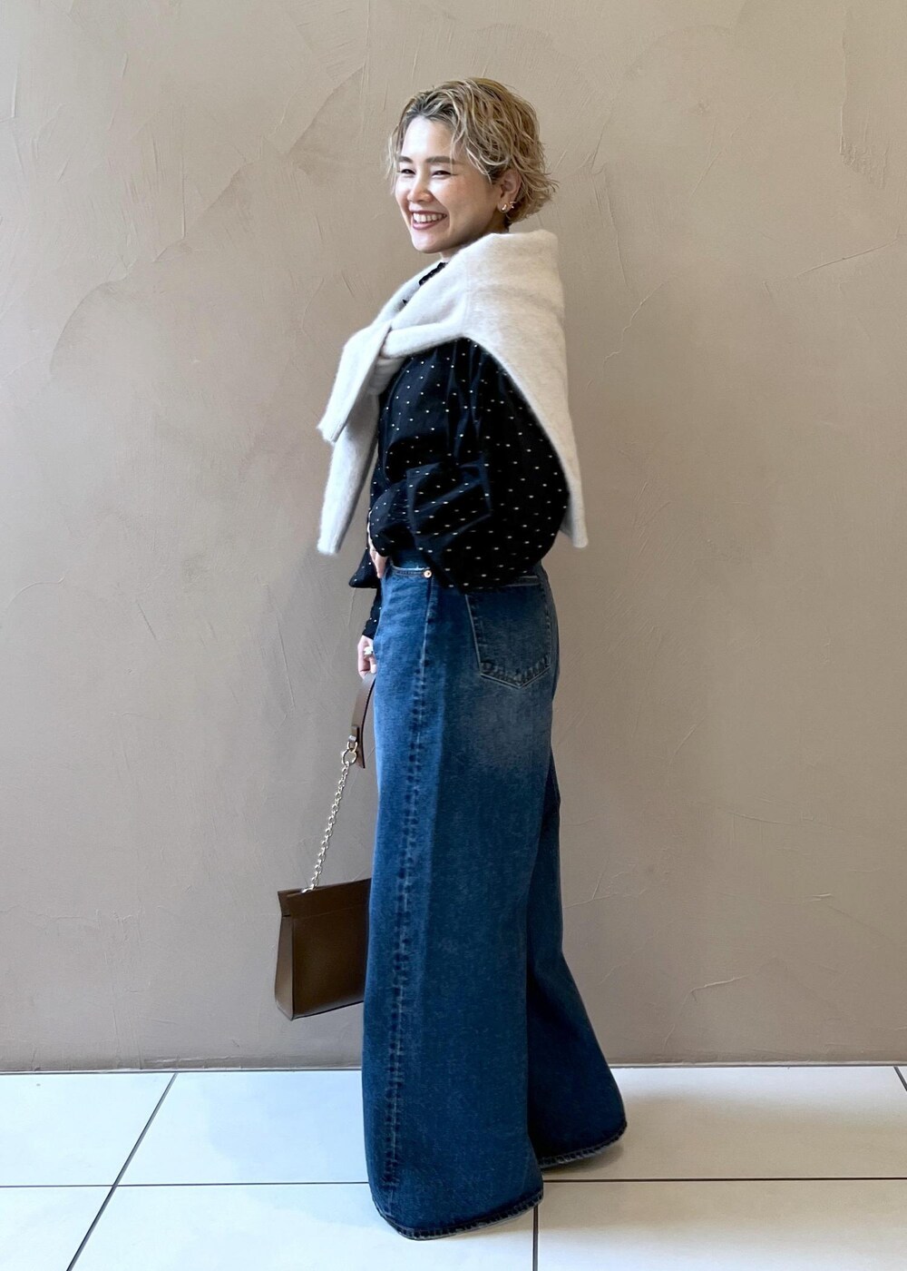 グレー系のニット/セーター、ブルー系のデニムパンツ、ブラウン系のショルダーバッグを着用したレディースの秋コーディネートの5枚目の写真