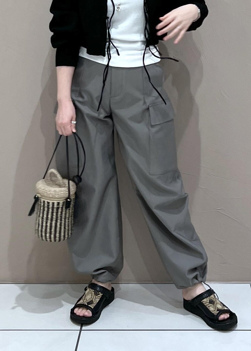 ブラック系のニット/セーター、グレー系のカーゴパンツ、ホワイト系のショルダーバッグを着用したレディースの春コーディネートの6枚目の写真