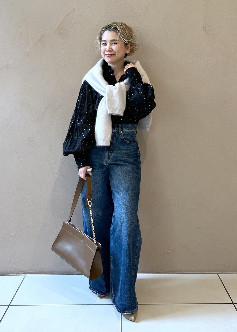 グレー系のニット/セーター、ブルー系のデニムパンツ、ブラウン系のショルダーバッグを着用したレディースの秋コーディネートの4枚目の写真