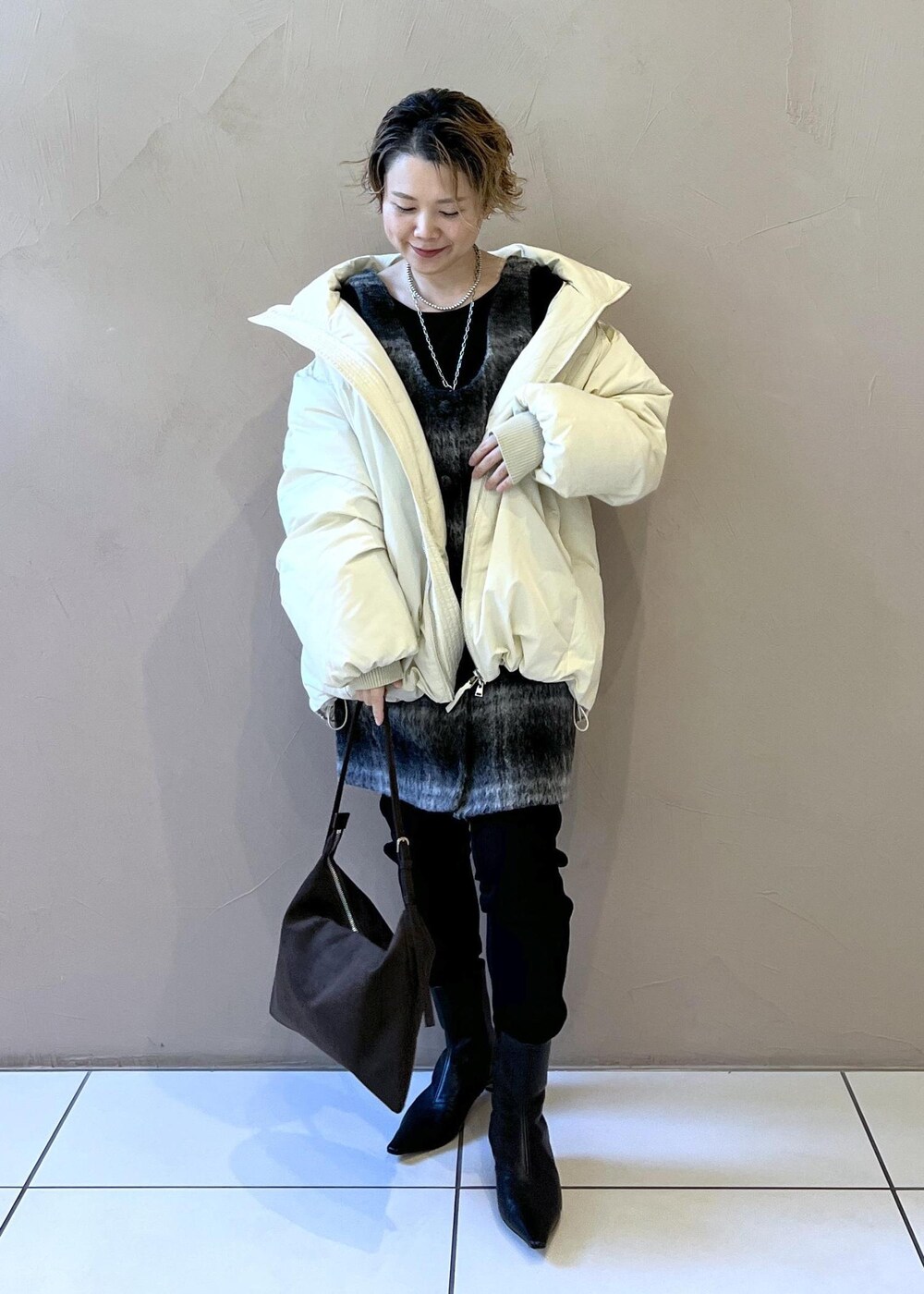 ホワイト系のダウンジャケット/コート、グレー系のジャンパースカート、ブラウン系のショルダーバッグを着用したレディースの秋コーディネートの5枚目の写真