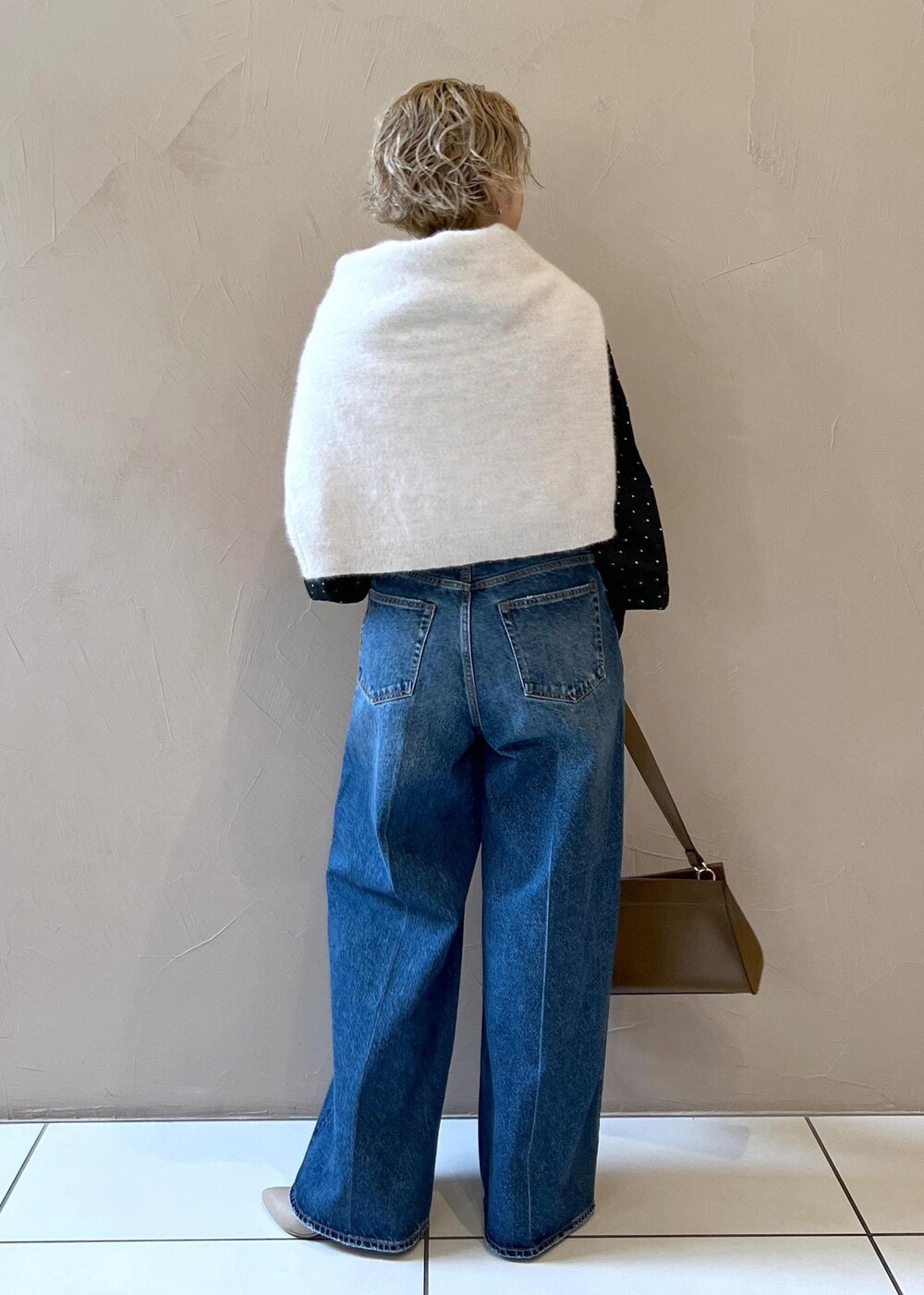 グレー系のニット/セーター、ブルー系のデニムパンツ、ブラウン系のショルダーバッグを着用したレディースの秋コーディネートの6枚目の写真