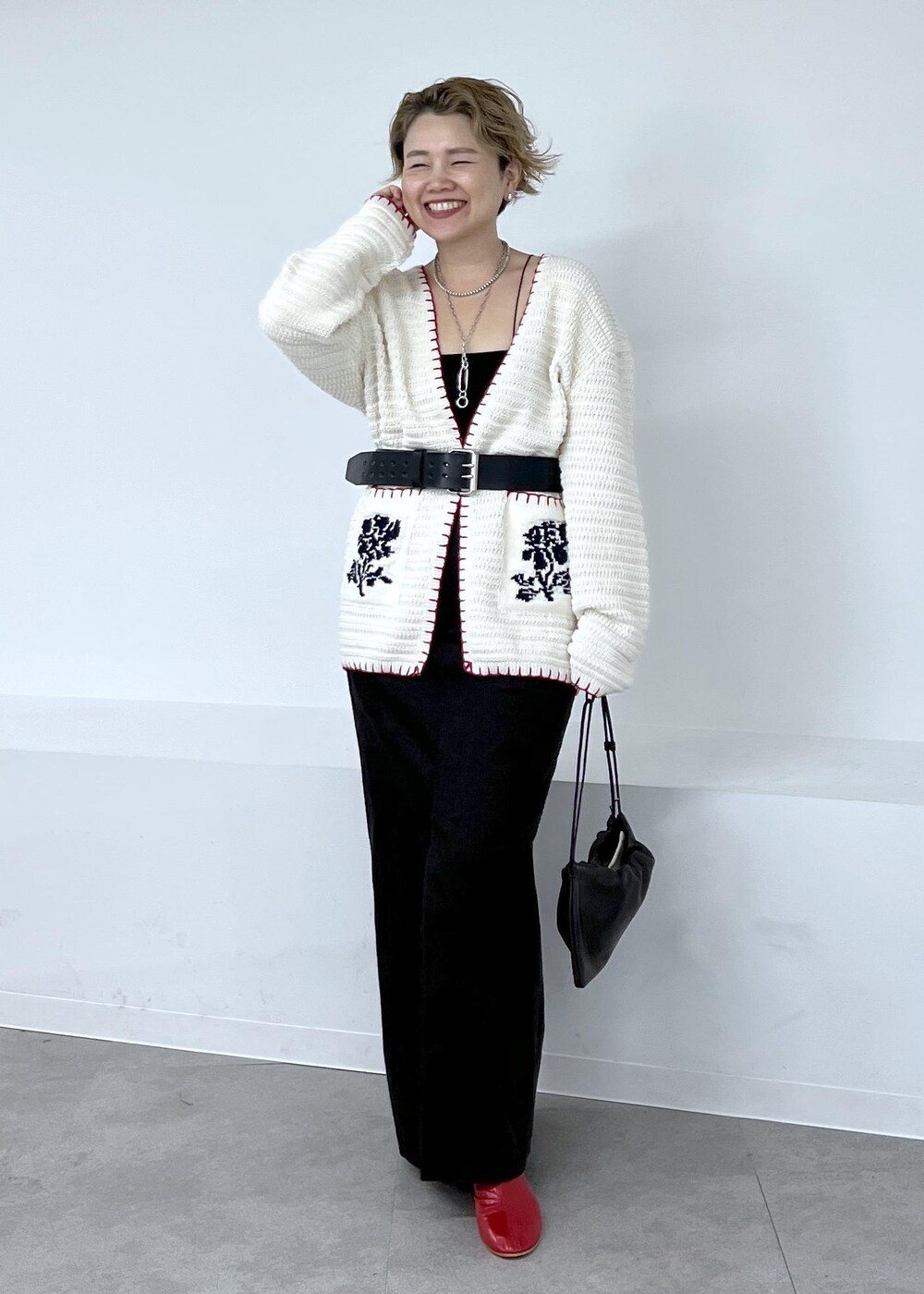 グレー系のスカート、ホワイト系のニット/セーター、レッド系のブーツを着用したレディースの秋コーディネートの3枚目の写真