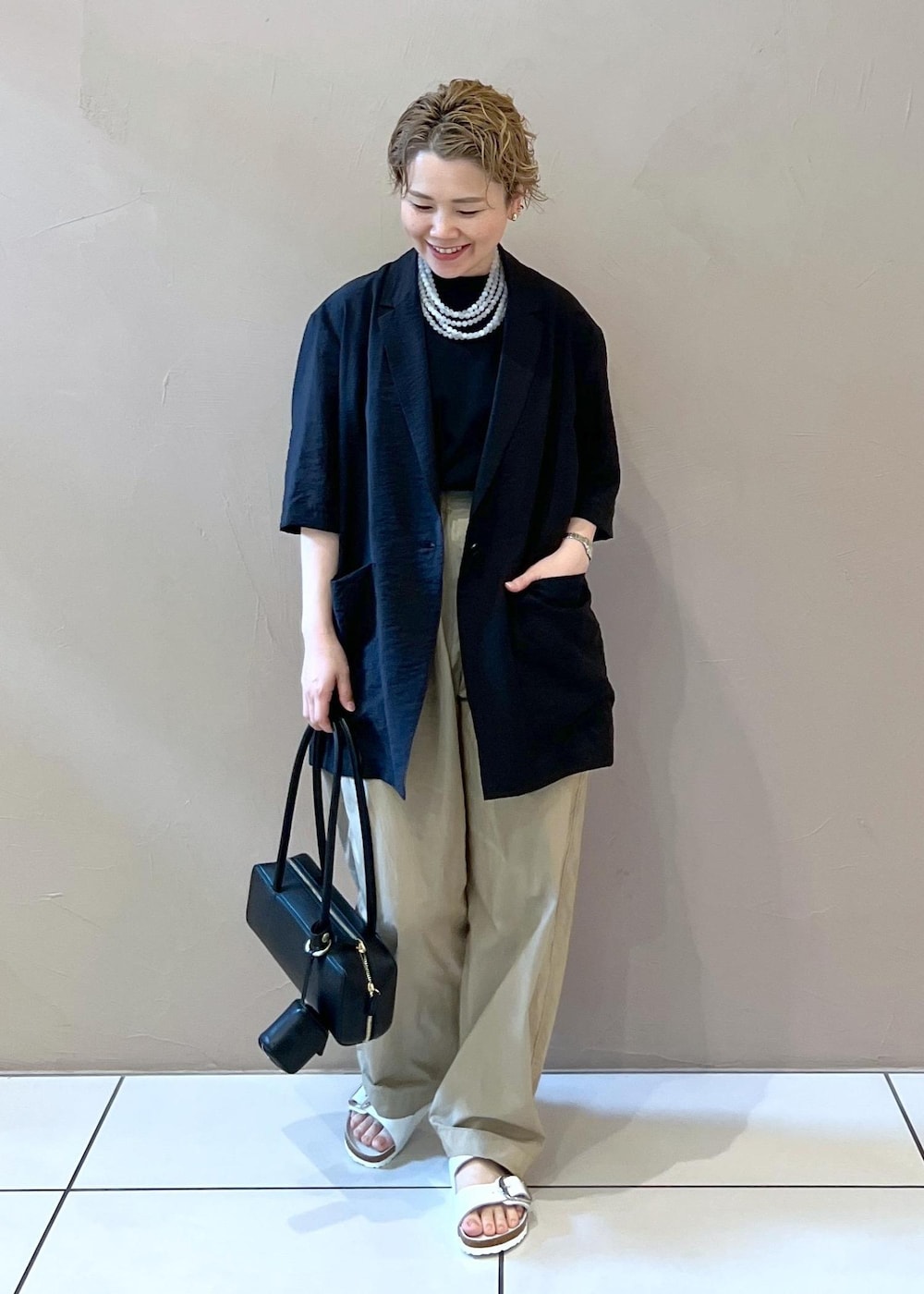 ベージュ系のその他パンツ、ブラック系のショルダーバッグ、ホワイト系のサンダルを着用したレディースの夏コーディネートの3枚目の写真