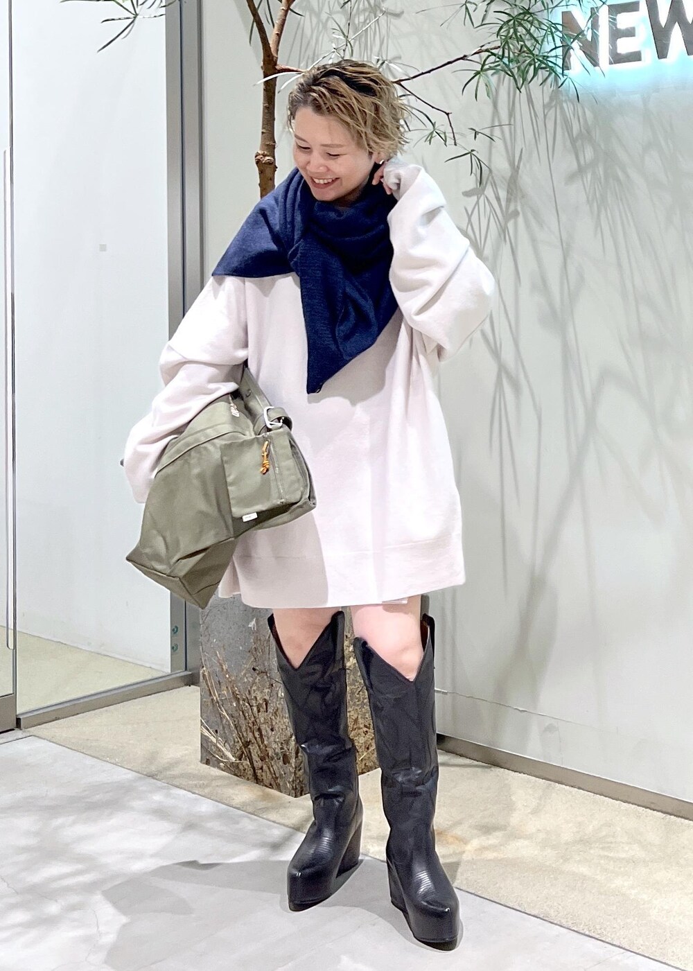 ブラック系のブーツ、グリーン系のトートバッグを着用したレディースの秋コーディネートの2枚目の写真