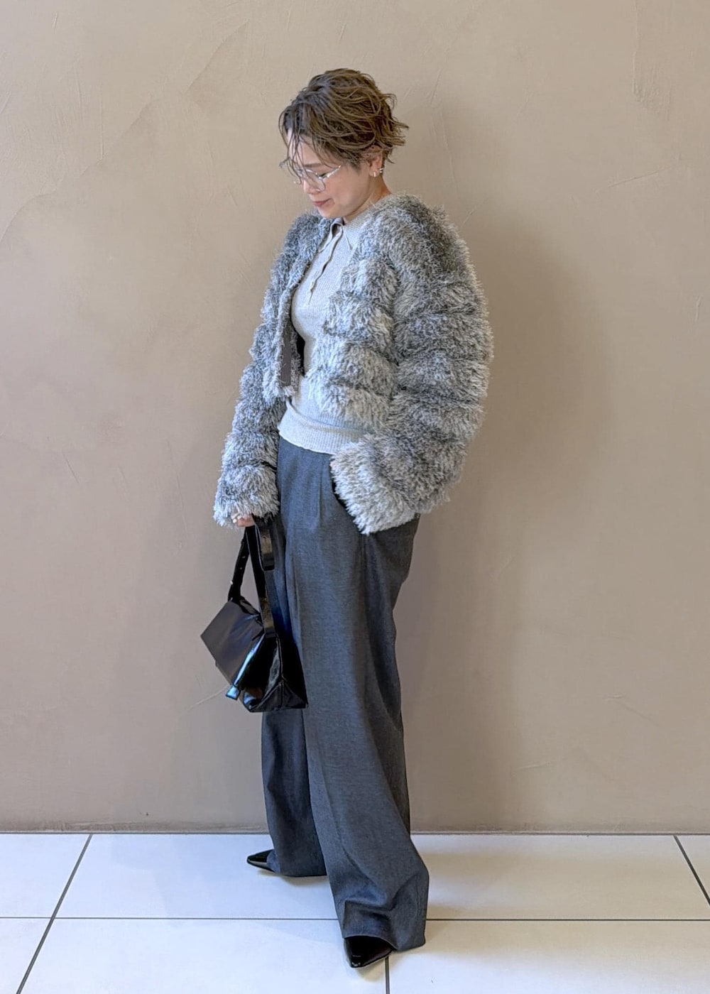 ブラック系のショルダーバッグ、グレー系のスラックス、グレー系のカーディガン/ボレロを着用したレディースの冬コーディネートの3枚目の写真