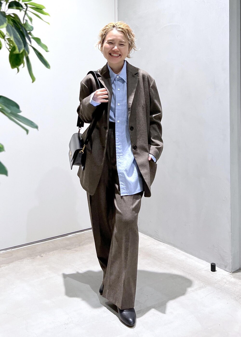 ブルー系のシャツ/ブラウス、ブラック系のショルダーバッグ、ブラウン系のスラックスを着用したレディースの秋コーディネートの2枚目の写真