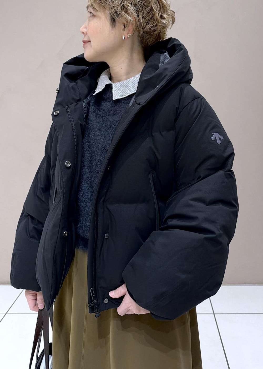 ブラウン系のスカート、ブラック系のダウンジャケット/コート、グレー系のニット/セーターを着用したレディースの冬コーディネートの7枚目の写真