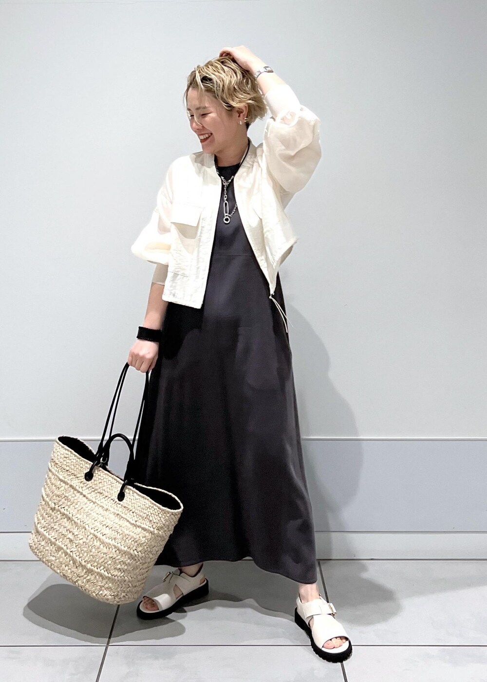ホワイト系のサンダル、ホワイト系のブルゾン、グレー系のワンピースを着用したレディースの春コーディネートの3枚目の写真
