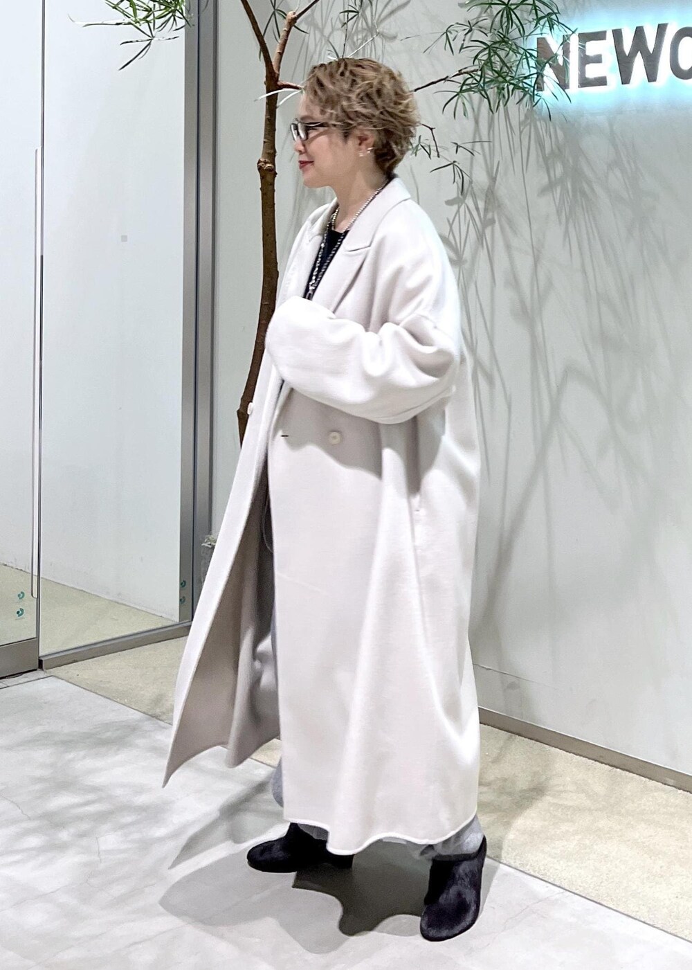 ホワイト系のチェスターコート、ブラック系のスウェット、ブラウン系のショルダーバッグを着用したレディースの秋コーディネートの5枚目の写真