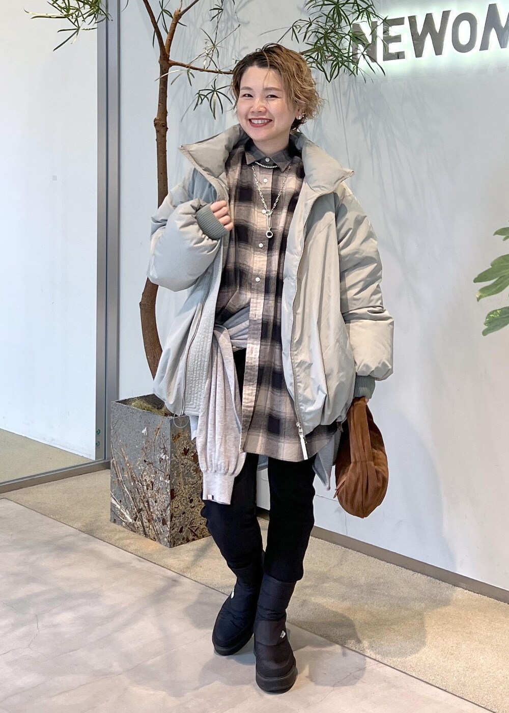 グリーン系のダウンジャケット/コート、ブラウン系のハンドバッグ、ブラック系のブーツを着用したレディースの秋コーディネートの9枚目の写真