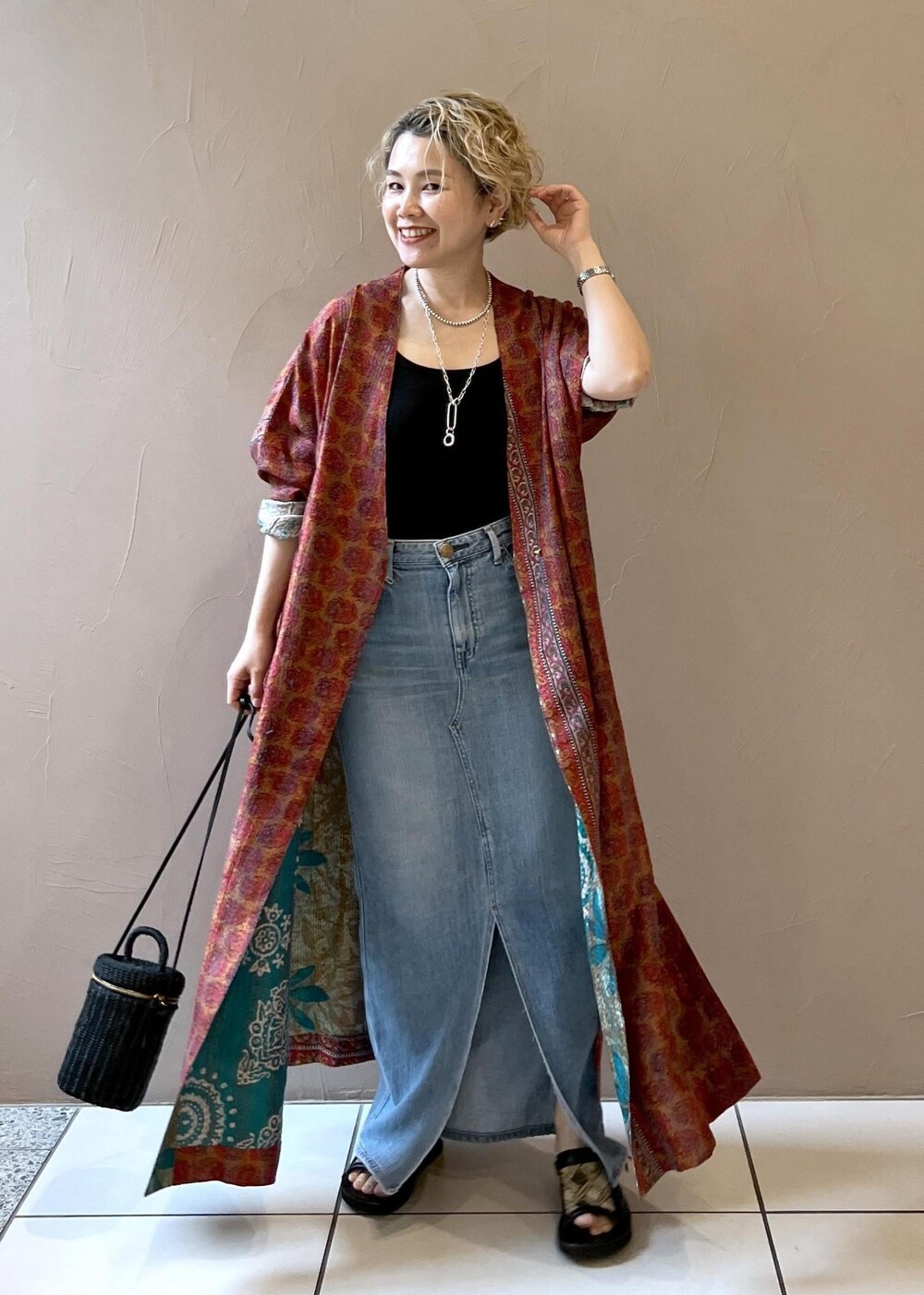 ブラック系のショルダーバッグ、ブラック系のタンクトップ、ブルー系のデニムスカートを着用したレディースの春コーディネートの5枚目の写真