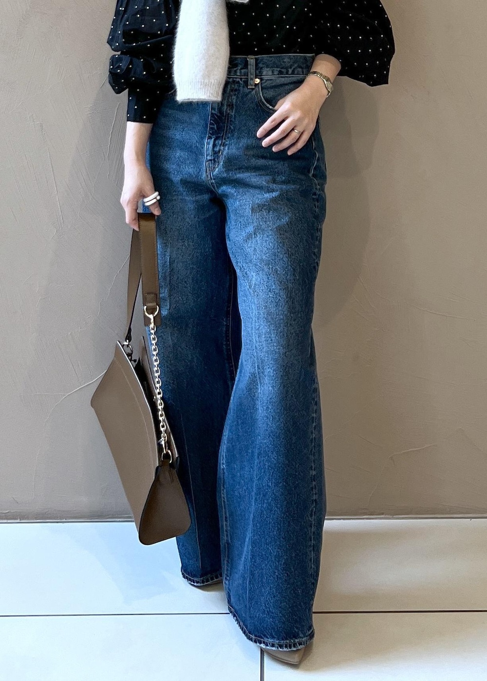 グレー系のニット/セーター、ブルー系のデニムパンツ、ブラウン系のショルダーバッグを着用したレディースの秋コーディネートの9枚目の写真
