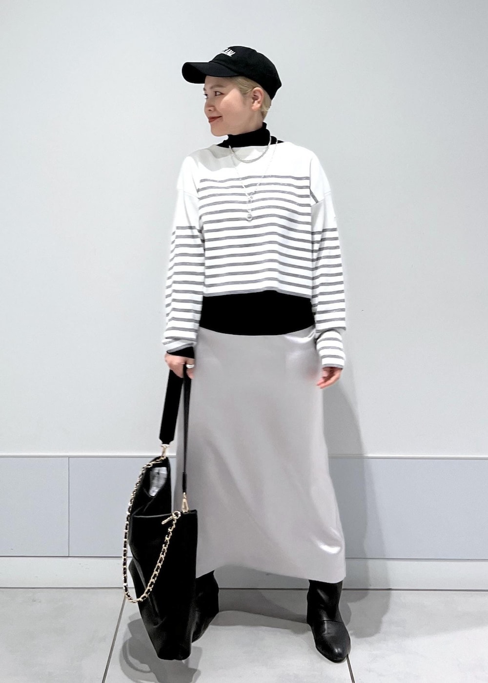 ブラック系のブーツ、ブラック系のTシャツ/カットソー、シルバー系のスカートを着用したレディースの冬コーディネートの2枚目の写真