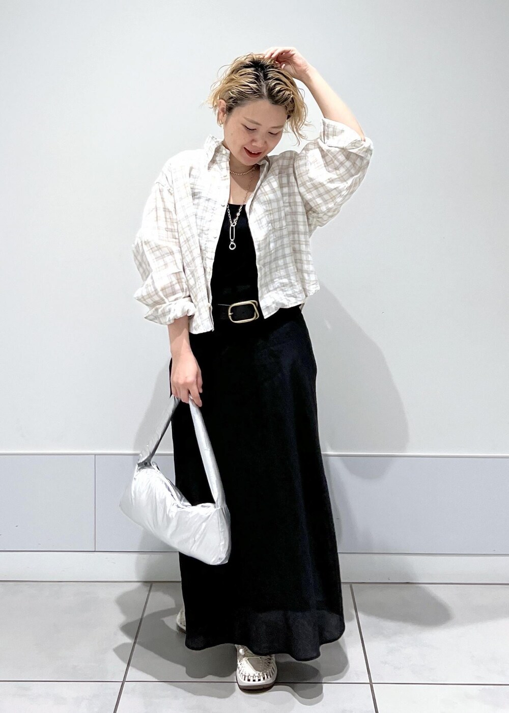 シルバー系のハンドバッグ、ホワイト系のサンダル、ブラック系のスカートを着用したレディースの春コーディネートの2枚目の写真