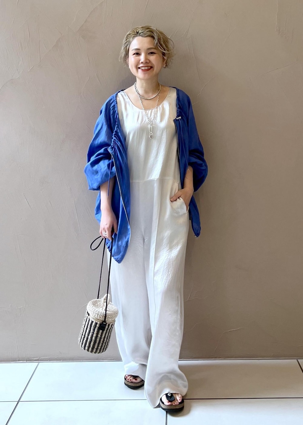 ホワイト系のショルダーバッグ、ブルー系のブルゾン、ホワイト系のつなぎ/オールインワンを着用したレディースの夏コーディネートの4枚目の写真