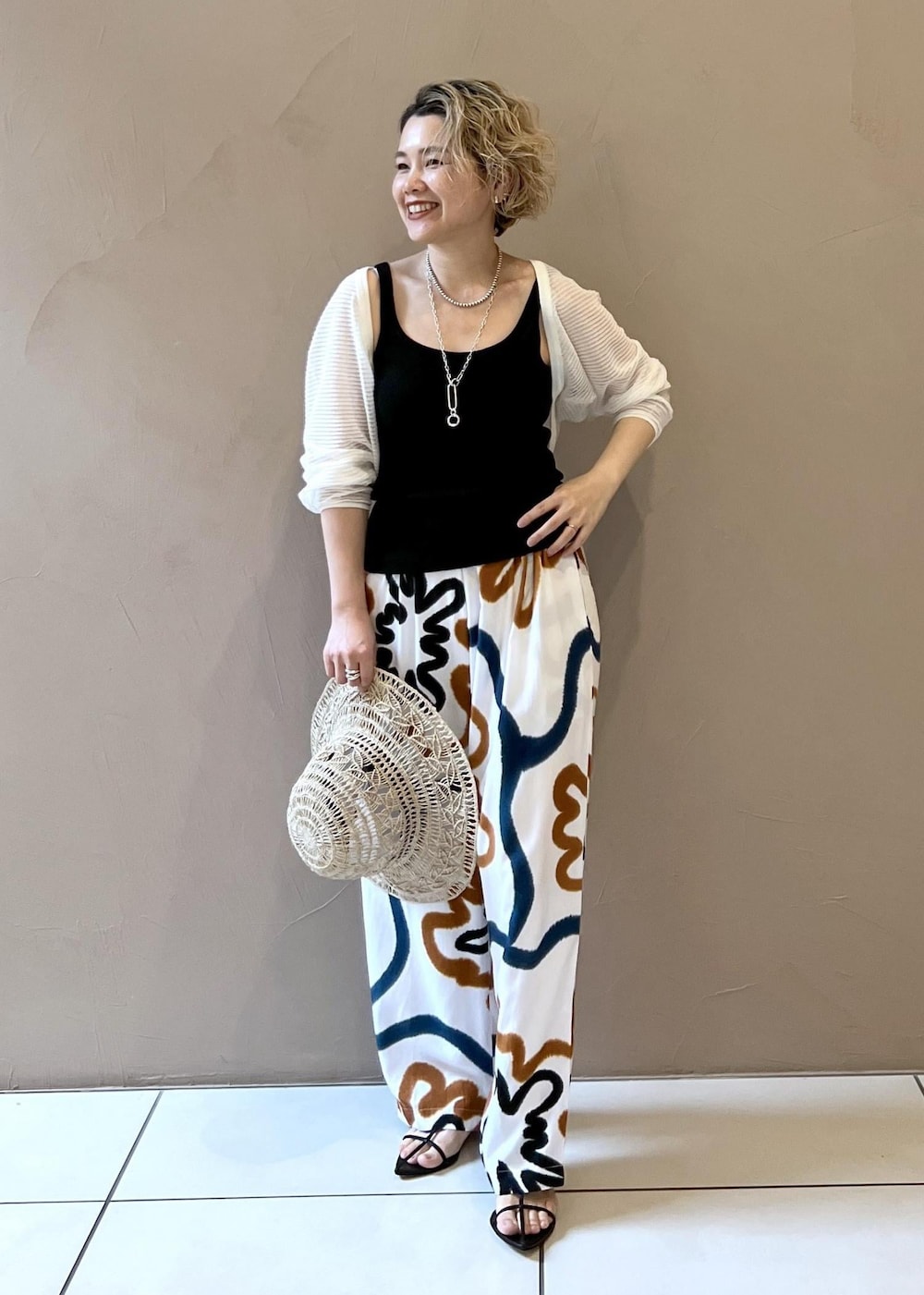 ブラック系のサンダル、ブラック系のタンクトップ、ホワイト系のカーディガン/ボレロを着用したレディースの春コーディネートの2枚目の写真