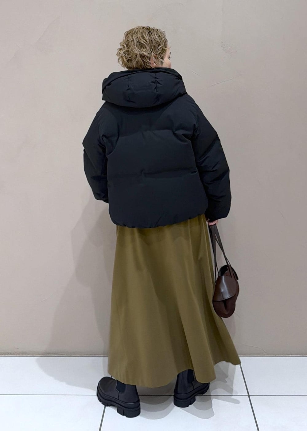 ブラウン系のスカート、ブラック系のダウンジャケット/コート、グレー系のニット/セーターを着用したレディースの冬コーディネートの6枚目の写真