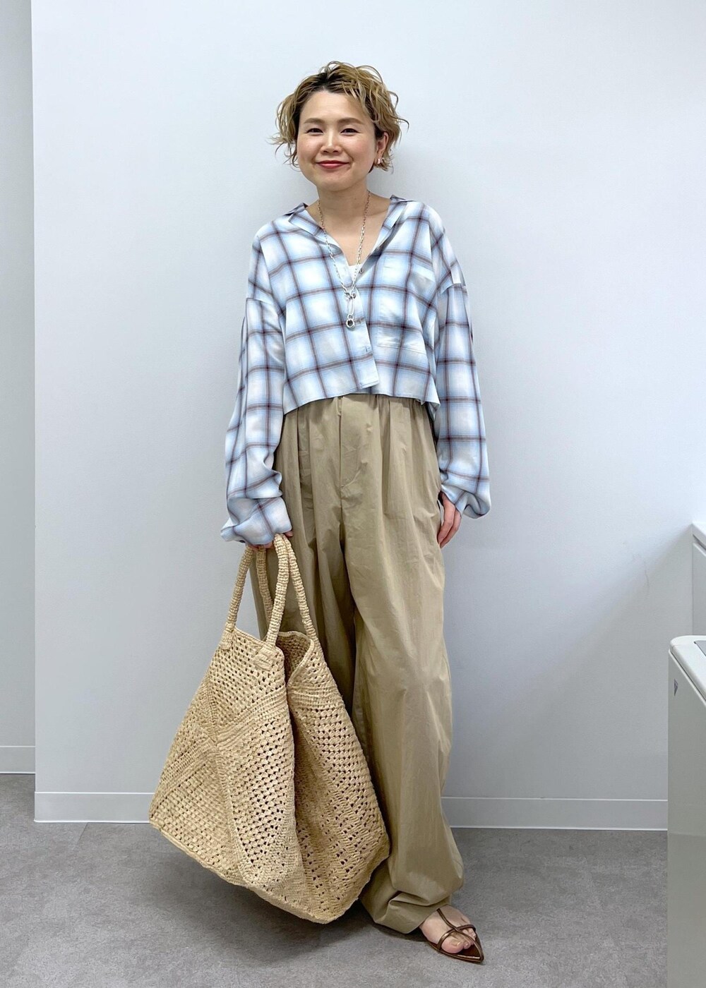 ホワイト系のかごバッグ、その他のサンダル、ベージュ系のその他パンツを着用したレディースの春コーディネートの3枚目の写真
