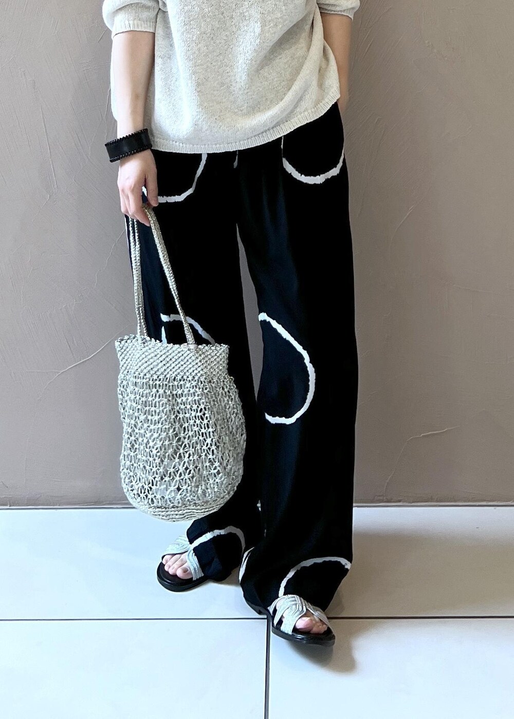 ゴールド系のハンドバッグ、シルバー系のサンダル、ホワイト系のニット/セーターを着用したレディースの春コーディネートの6枚目の写真