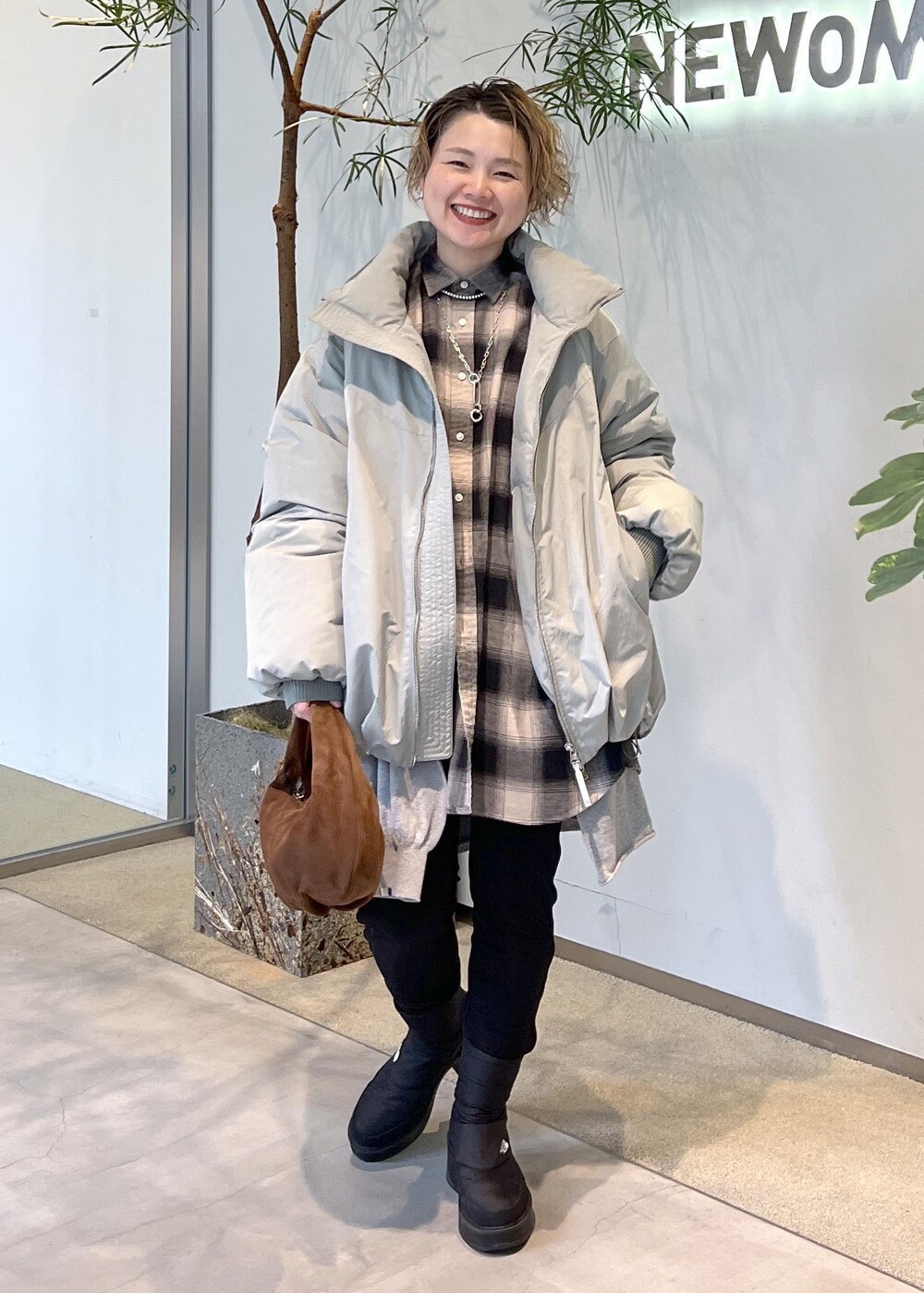 グリーン系のダウンジャケット/コート、ブラウン系のハンドバッグ、ブラック系のブーツを着用したレディースの秋コーディネートの10枚目の写真