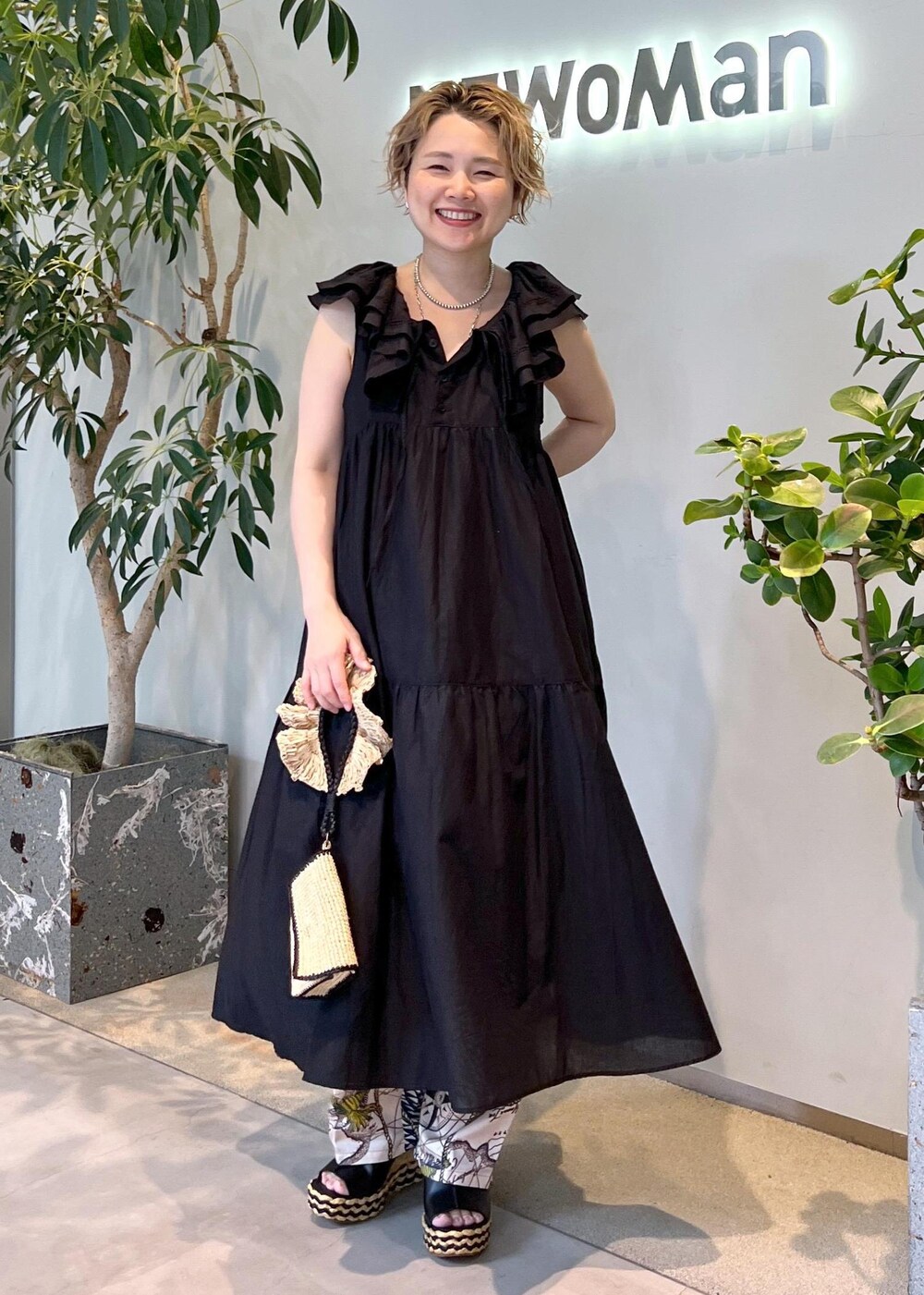 ブラック系のワンピース、ホワイト系のハンドバッグ、ブラック系のサンダルを着用したレディースの夏コーディネートの2枚目の写真