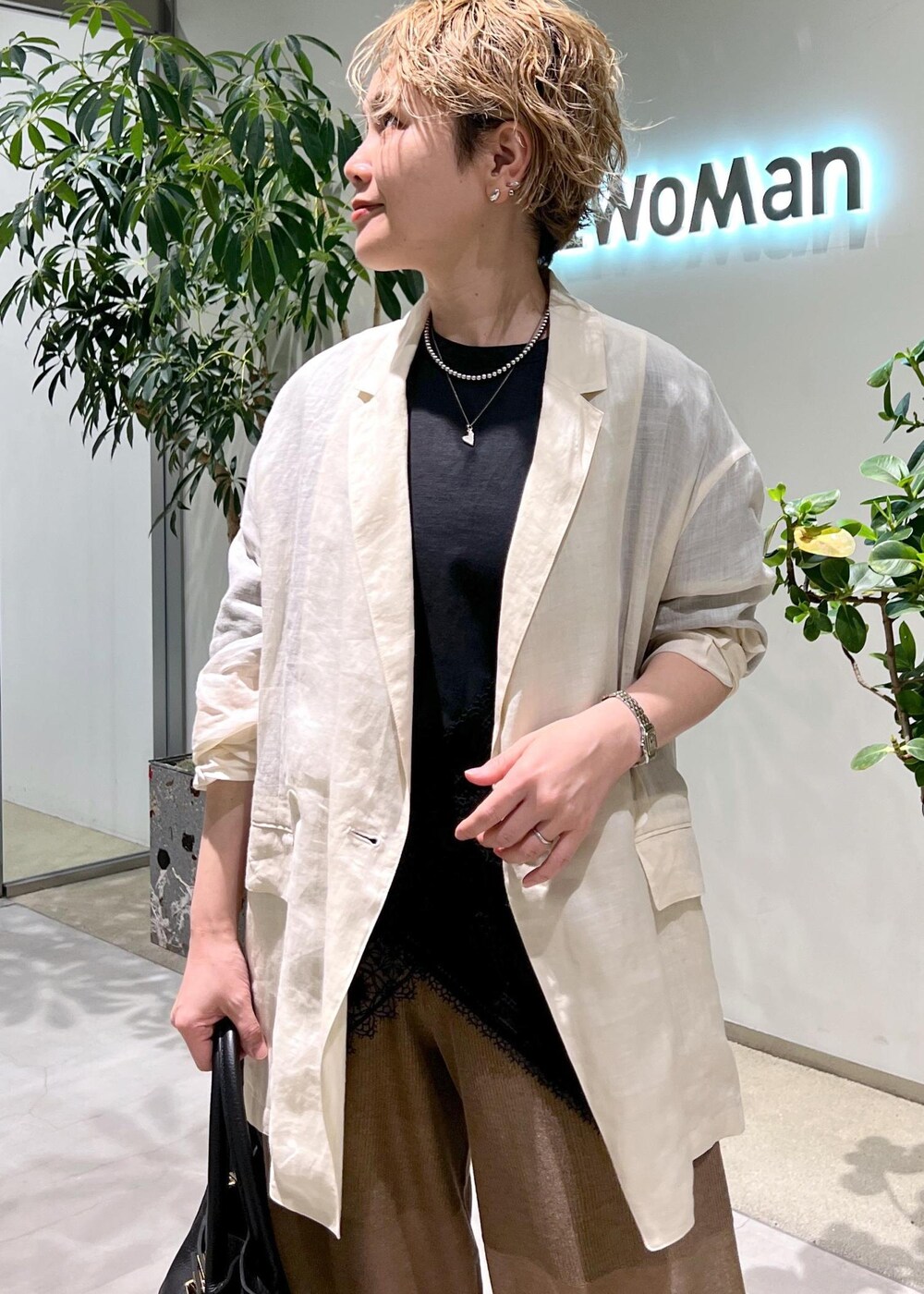 ブラック系のショルダーバッグ、ブラック系のTシャツ/カットソー、ホワイト系のテーラードジャケットを着用したレディースの夏コーディネートの5枚目の写真