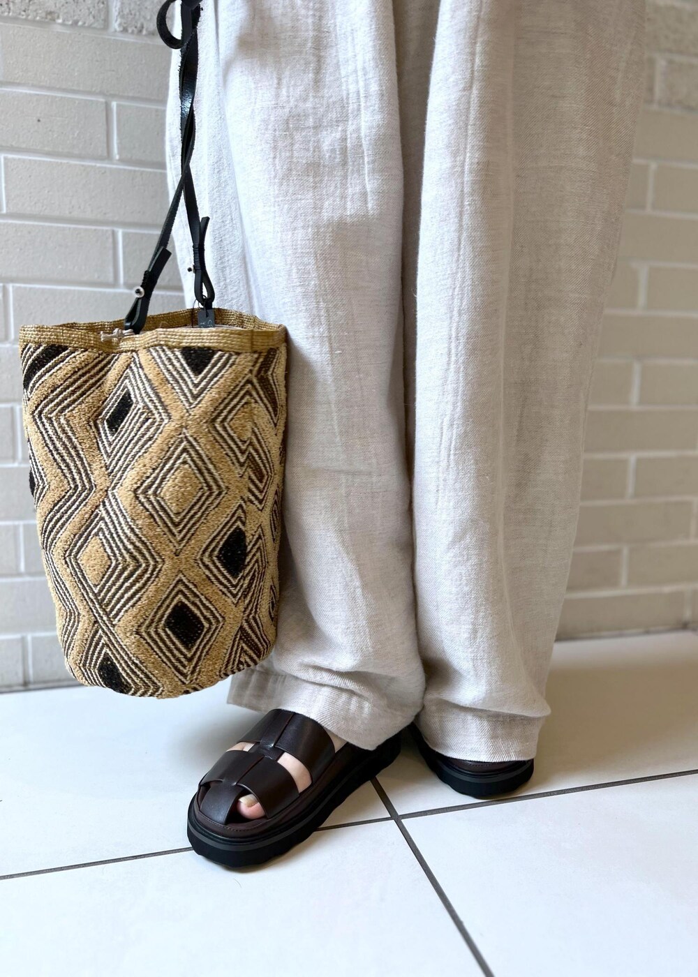 ブラウン系のサンダル、ホワイト系のカーディガン/ボレロ、ホワイト系のスラックスを着用したレディースの夏コーディネートの6枚目の写真