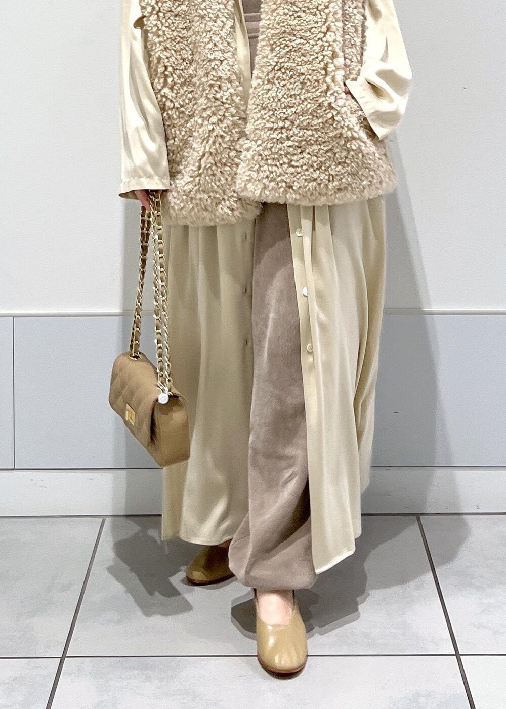 グレー系のカーゴパンツ、ベージュ系のベスト、グレー系のキャミソールを着用したレディースの秋コーディネートの7枚目の写真