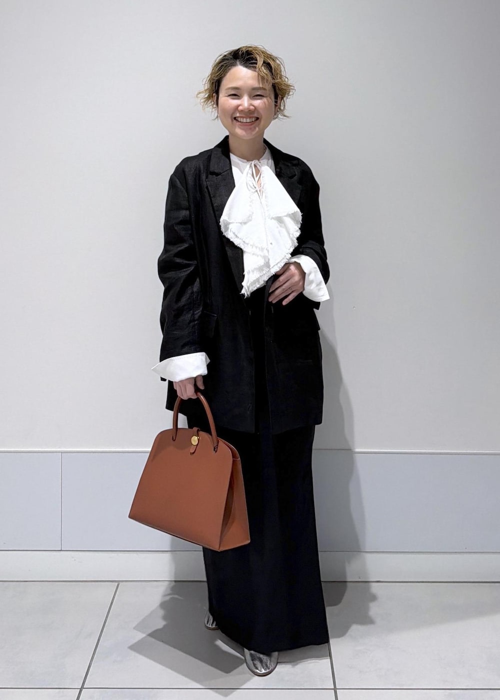 ブラック系のスカート、ブラック系のテーラードジャケット、ホワイト系のシャツ/ブラウスを着用したレディースの冬コーディネートの2枚目の写真