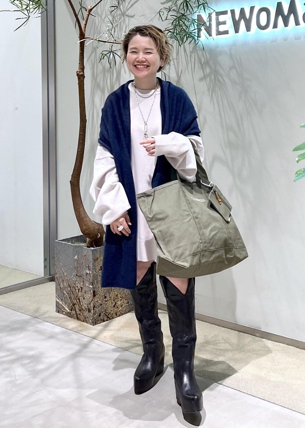 ブラック系のブーツ、グリーン系のトートバッグを着用したレディースの秋コーディネートの7枚目の写真