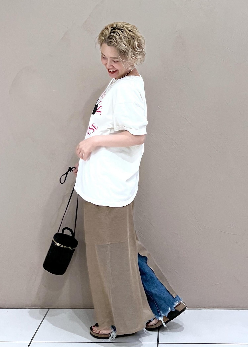 ブラック系のショルダーバッグ、ホワイト系のTシャツ/カットソー、ブルー系のデニムパンツを着用したレディースの夏コーディネートの5枚目の写真