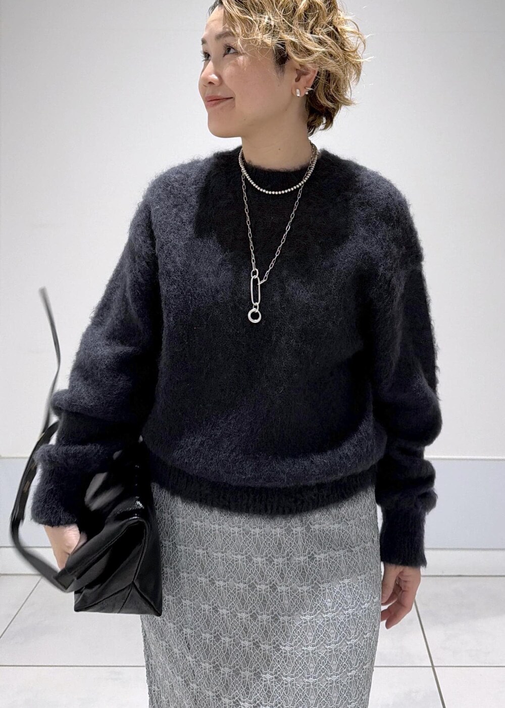 ブラック系のショルダーバッグ、グリーン系のスカート、ブラック系のブーツを着用したレディースの秋コーディネートの5枚目の写真