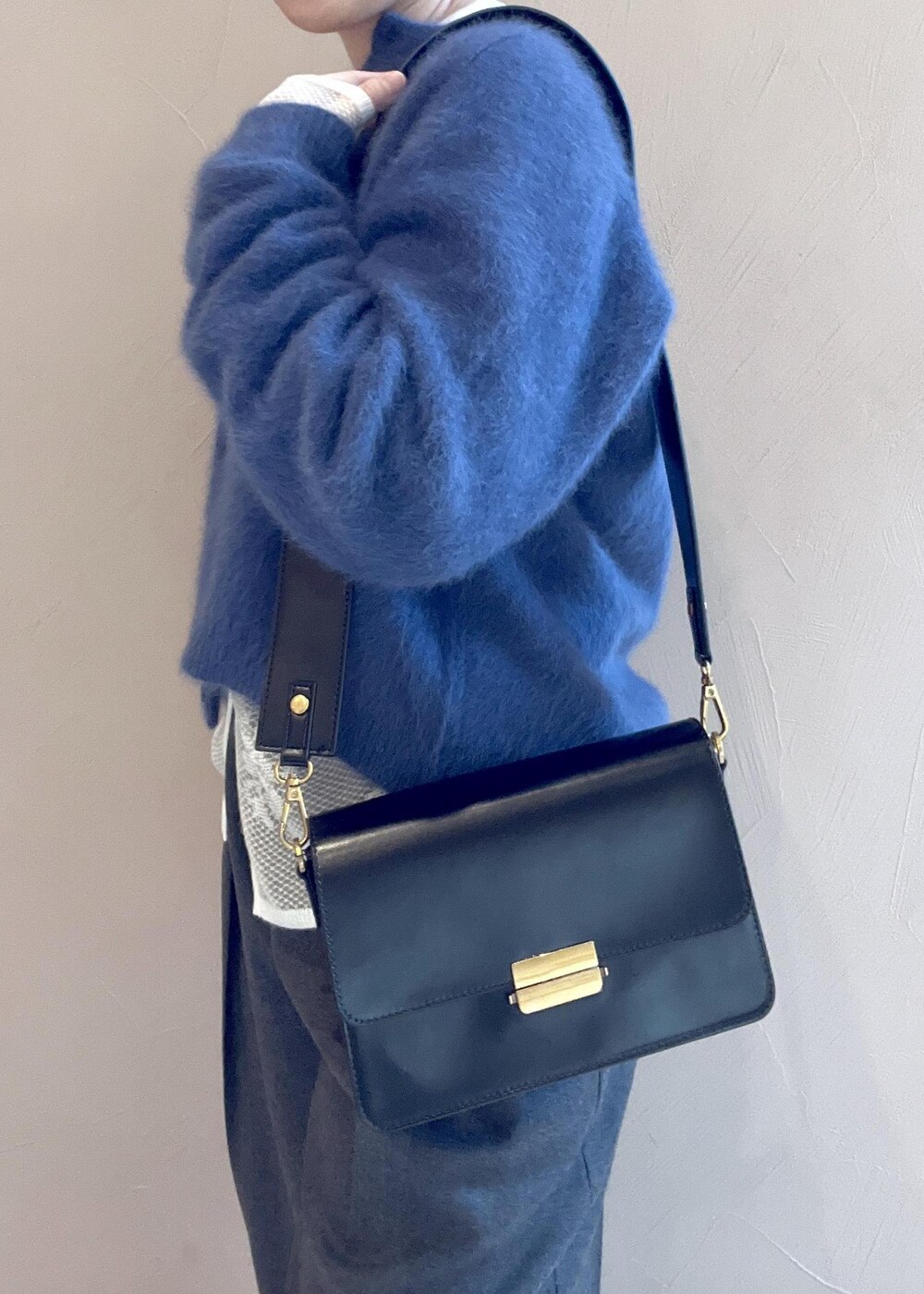 ブラック系のショルダーバッグ、ブルー系のカーディガン/ボレロ、グレー系のスラックスを着用したレディースの冬コーディネートの8枚目の写真