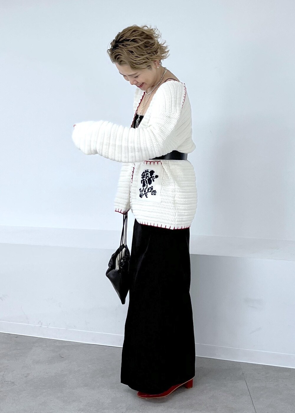 グレー系のスカート、ホワイト系のニット/セーター、レッド系のブーツを着用したレディースの秋コーディネートの4枚目の写真