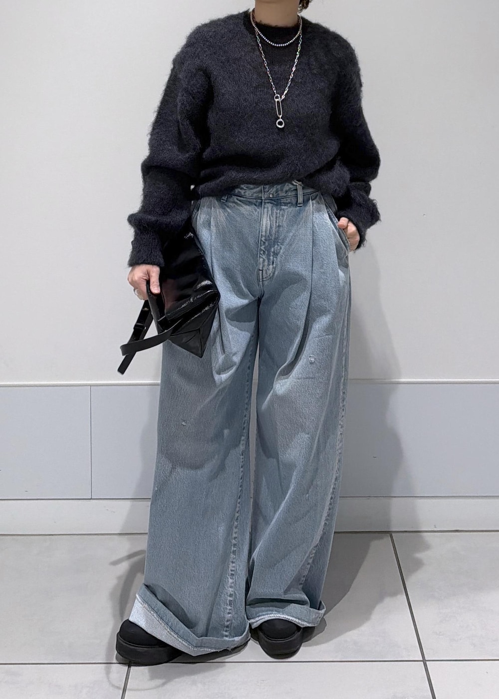 ブラック系のショルダーバッグ、ブラック系のブーツ、ブルー系のデニムパンツを着用したレディースの秋コーディネートの5枚目の写真