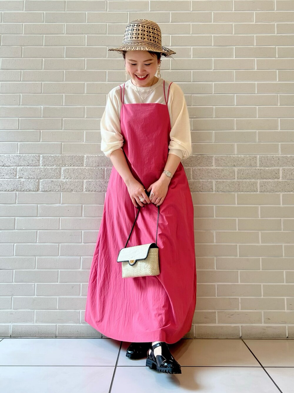 ピンク系のワンピース、ブラック系のショルダーバッグ、ブラック系のサンダルを着用したレディースの春コーディネートの2枚目の写真