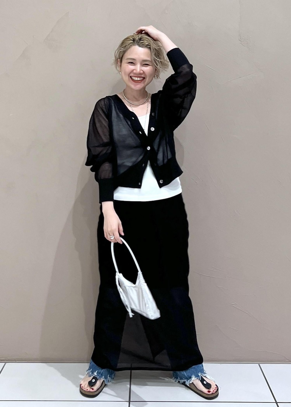 ホワイト系のタンクトップ、ブラック系のカーディガン/ボレロ、ブルー系のデニムパンツを着用したレディースの夏コーディネートの3枚目の写真