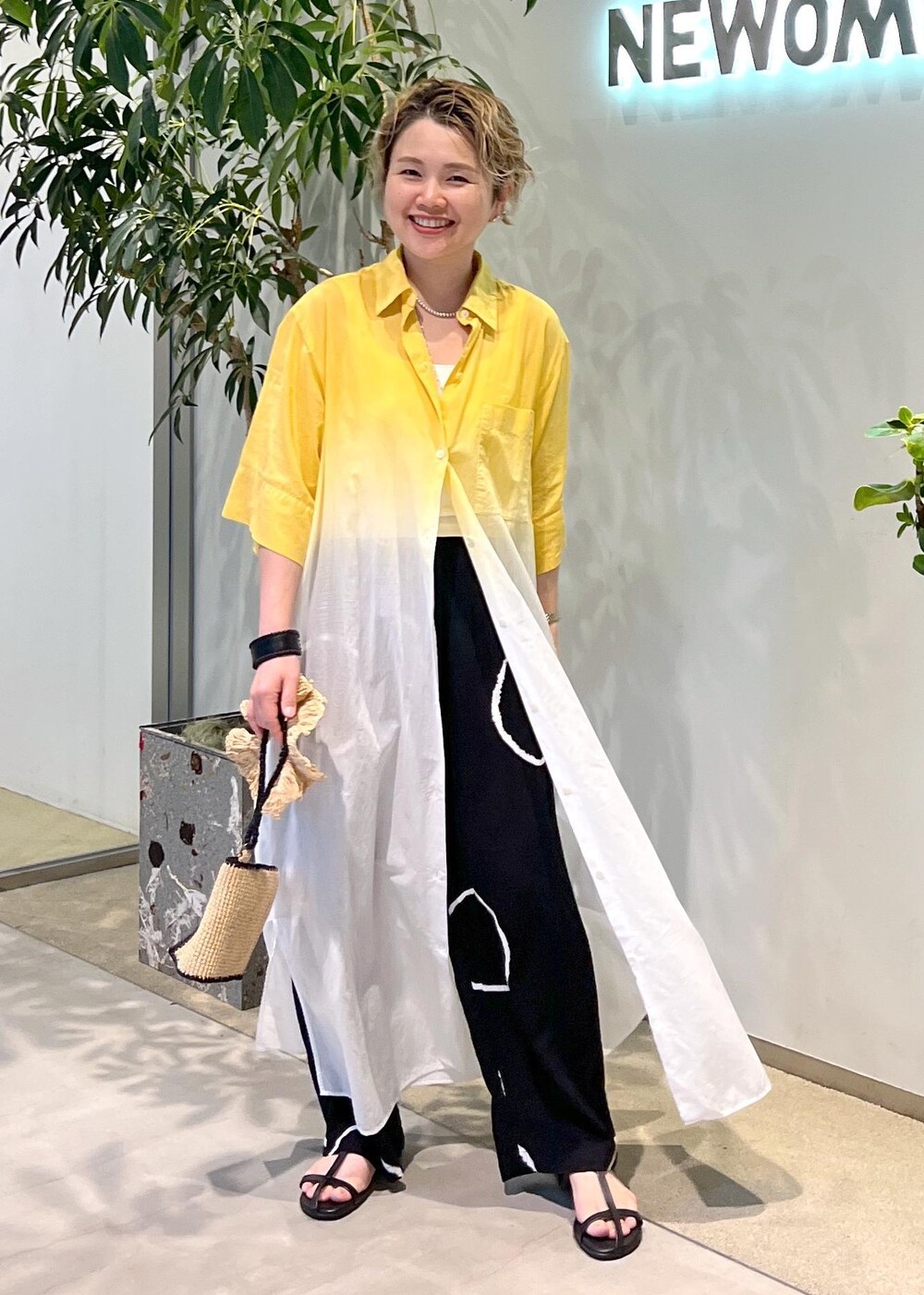 ブラック系のサンダル、ホワイト系のハンドバッグを着用したレディースの夏コーディネートの2枚目の写真