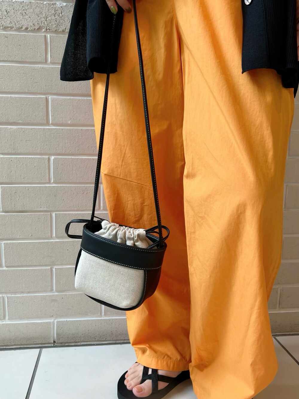 ブラック系のカーディガン/ボレロ、オレンジ系のパンツ、ブラック系のショルダーバッグを着用したレディースの夏コーディネートの5枚目の写真