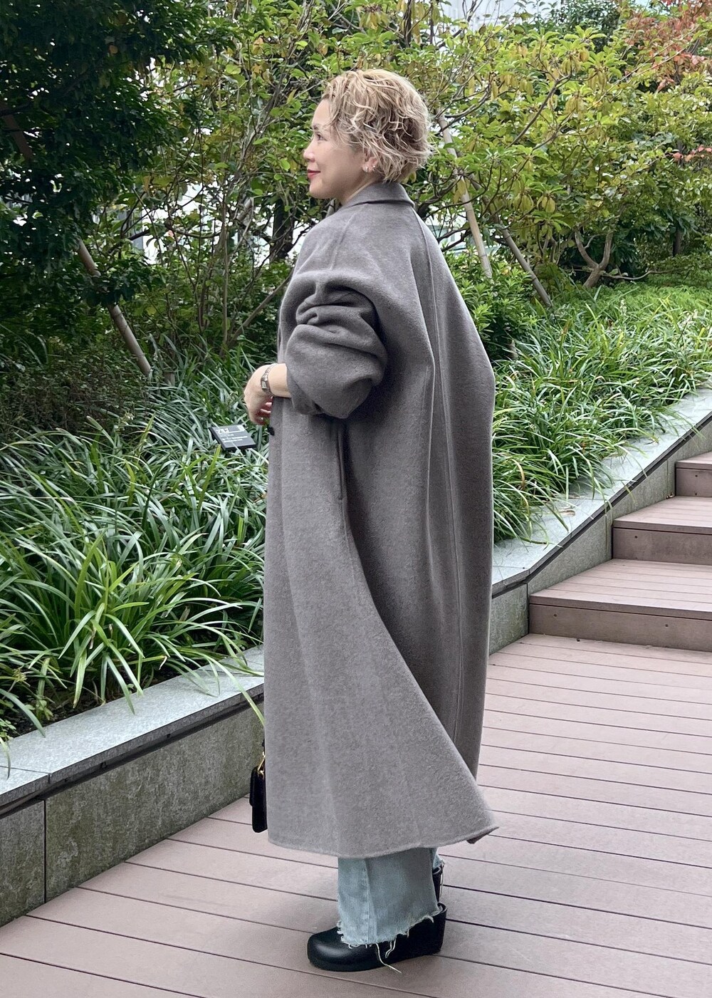 グレー系のニット/セーター、ブラック系のショルダーバッグ、ブラウン系のその他アウターを着用したレディースの秋コーディネートの6枚目の写真