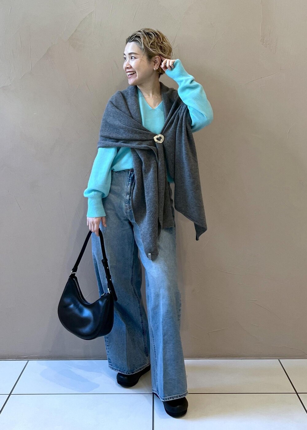 ブルー系のニット/セーター、ブルー系のデニムパンツ、ブラック系のスニーカーを着用したレディースの秋コーディネートの3枚目の写真