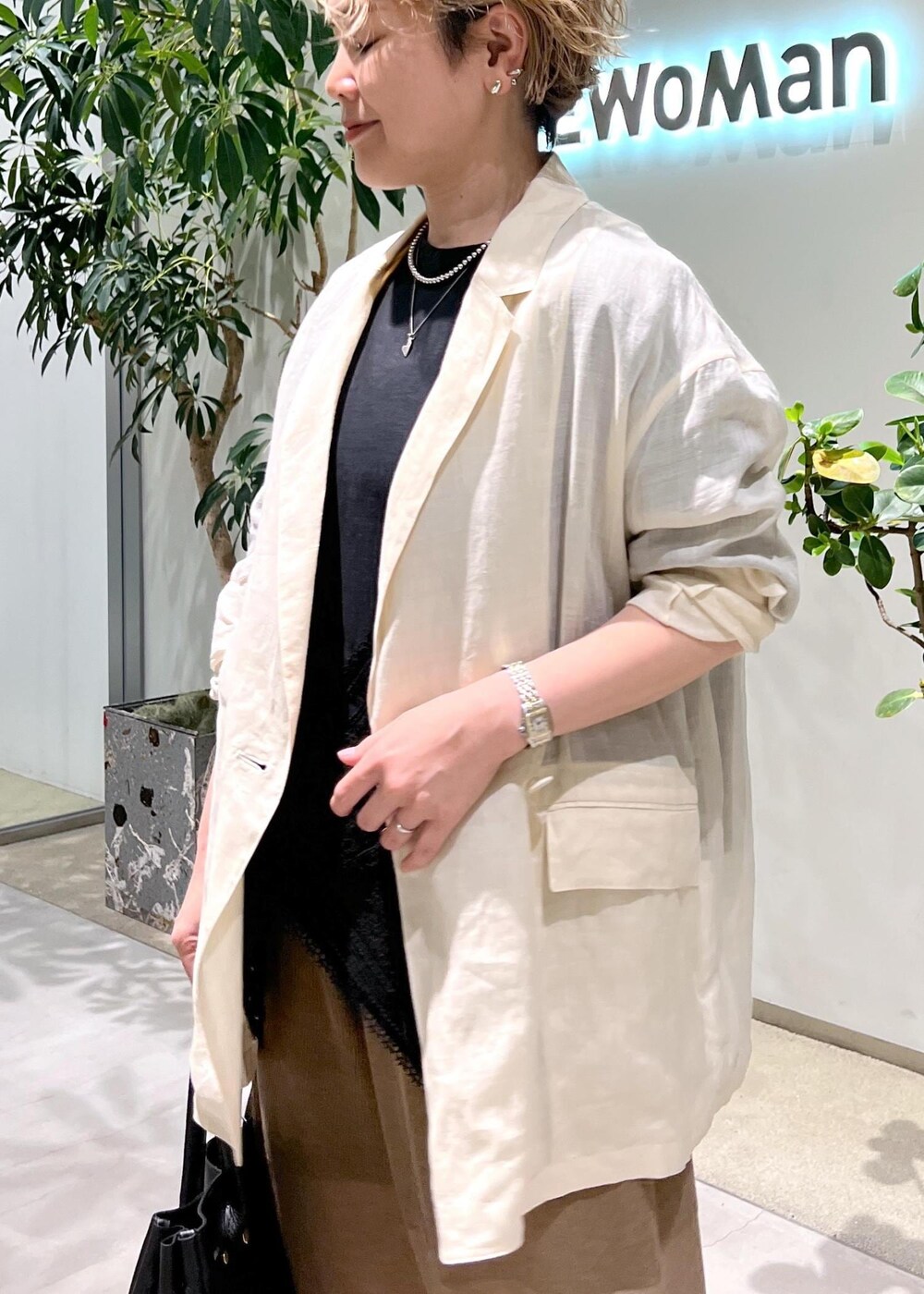 ブラック系のショルダーバッグ、ブラック系のTシャツ/カットソー、ホワイト系のテーラードジャケットを着用したレディースの夏コーディネートの6枚目の写真