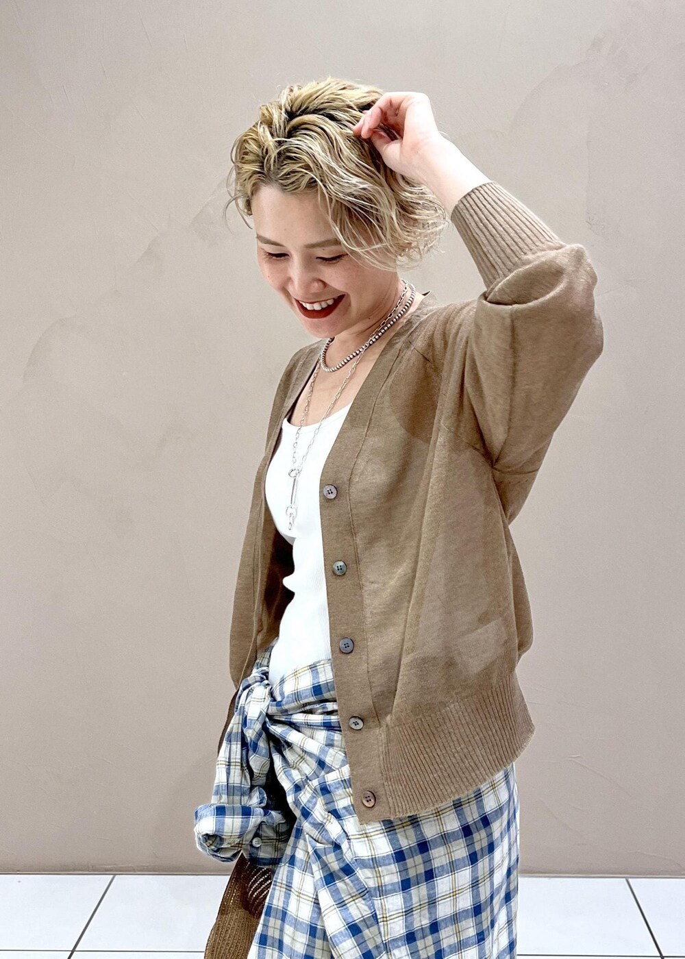 ホワイト系のタンクトップ、ゴールド系のカーディガン/ボレロ、ブルー系のデニムパンツを着用したレディースの夏コーディネートの6枚目の写真