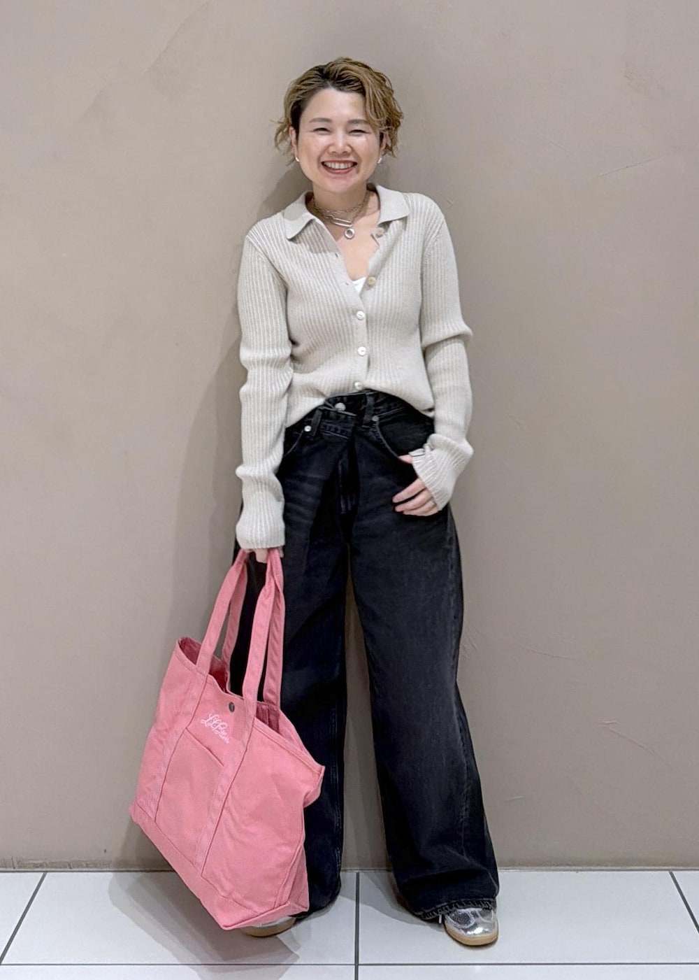 ベージュ系のカーディガン/ボレロ、ピンク系のトートバッグ、ブラック系のデニムパンツを着用したレディースの冬コーディネートの2枚目の写真