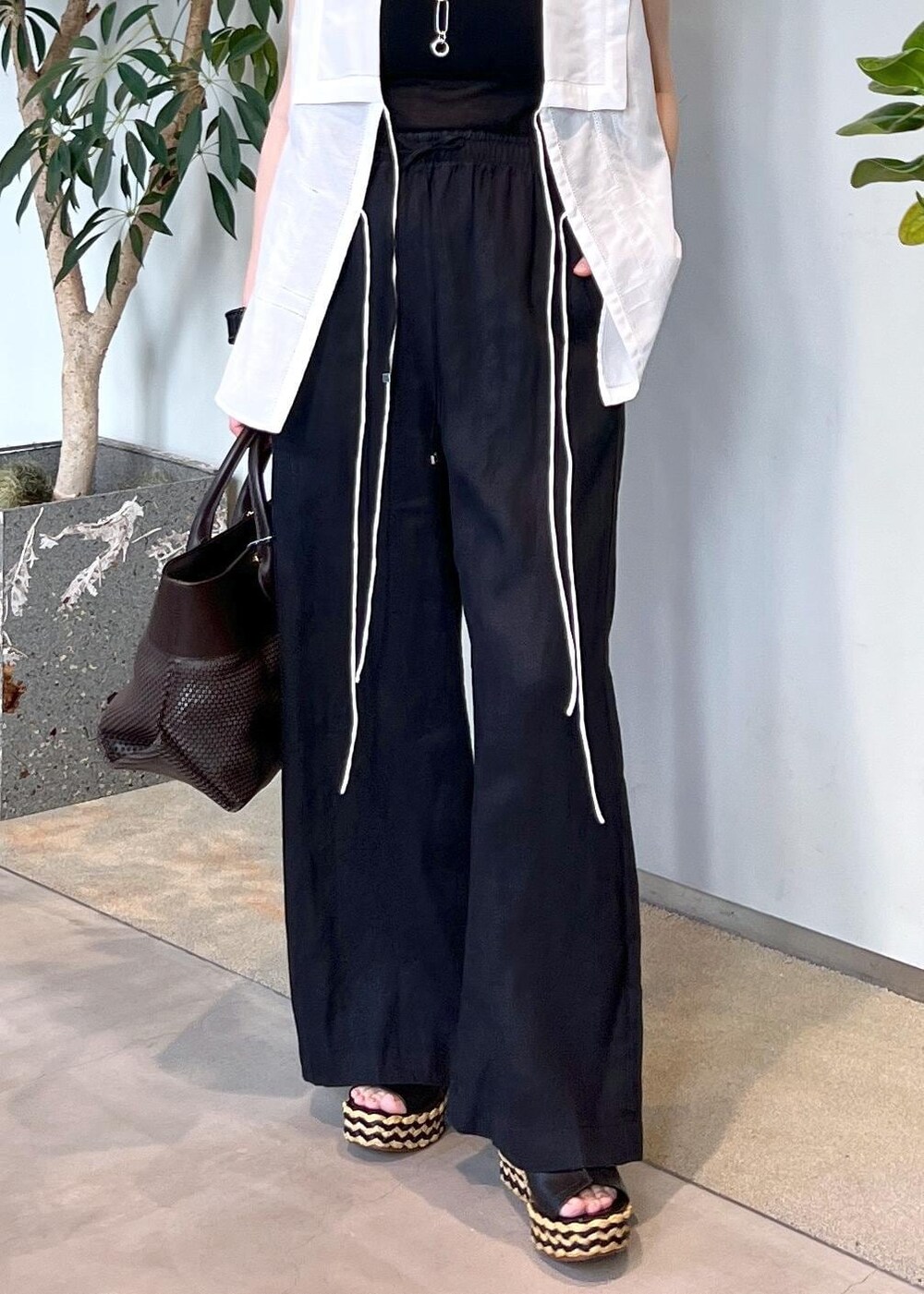 ブラック系のその他パンツ、ブラウン系のトートバッグ、ホワイト系のシャツ/ブラウスを着用したレディースの夏コーディネートの7枚目の写真