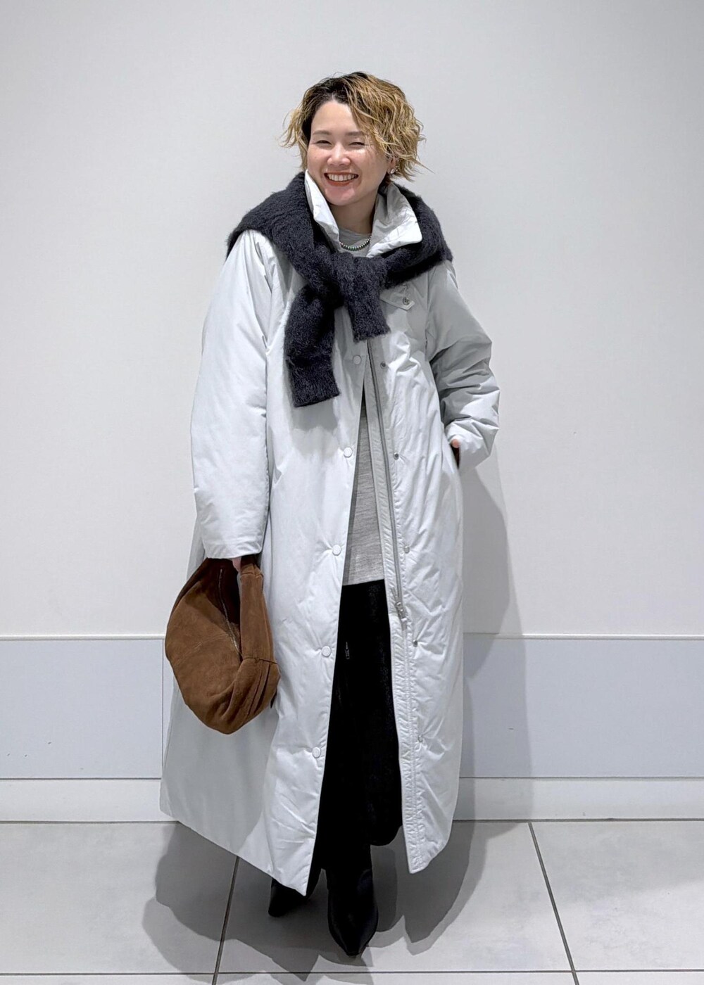 ブラック系のスカート、ブラウン系のハンドバッグ、グレー系のダウンジャケット/コートを着用したレディースの秋コーディネートの3枚目の写真