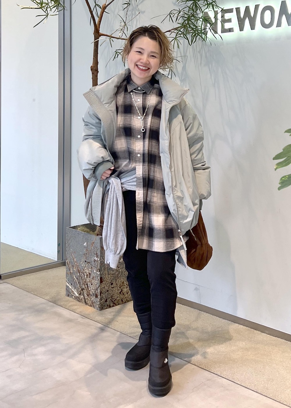 グリーン系のダウンジャケット/コート、ブラウン系のハンドバッグ、ブラック系のブーツを着用したレディースの秋コーディネートの2枚目の写真