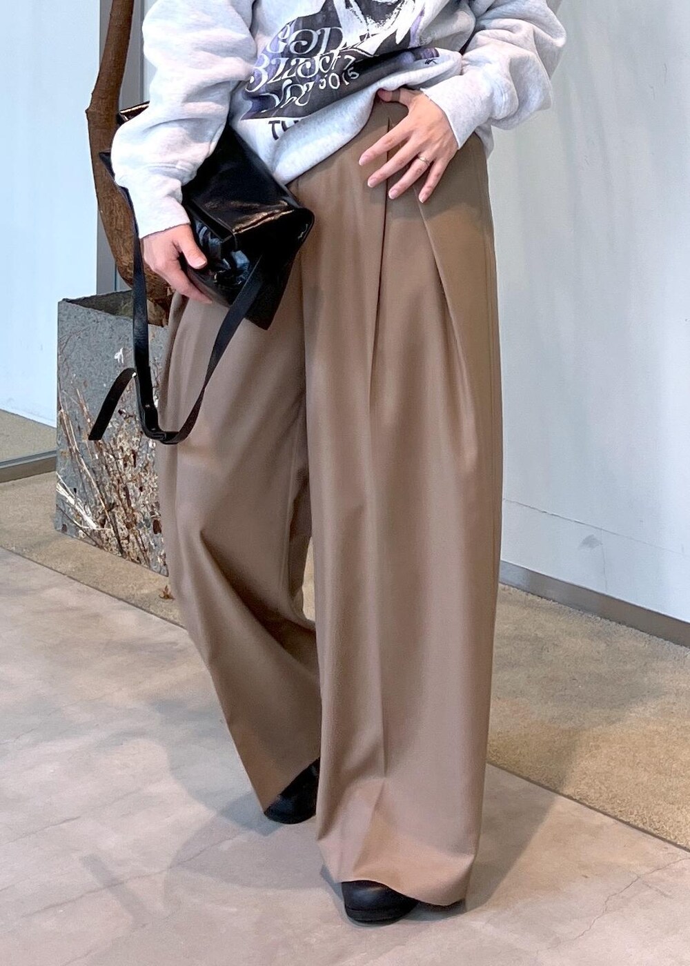 ベージュ系のスラックス、ブラック系のショルダーバッグ、ブラック系のスニーカーを着用したレディースの秋コーディネートの8枚目の写真