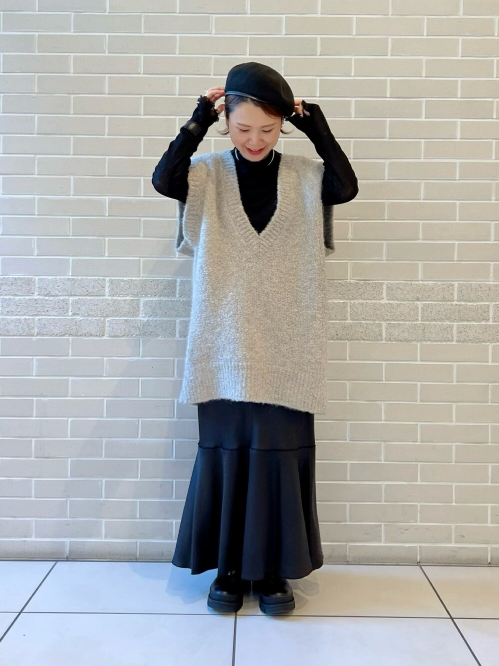 グレー系のニット/セーター、ブラック系のTシャツ/カットソー、ブラック系のスカートを着用したレディースの秋コーディネートの2枚目の写真